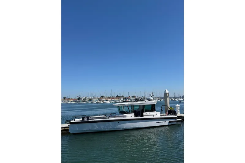 The Image of 2021 Axopar 28 Cabin BRABUS Trim Wet Bar docked in a marina under clear blue skies. - 0