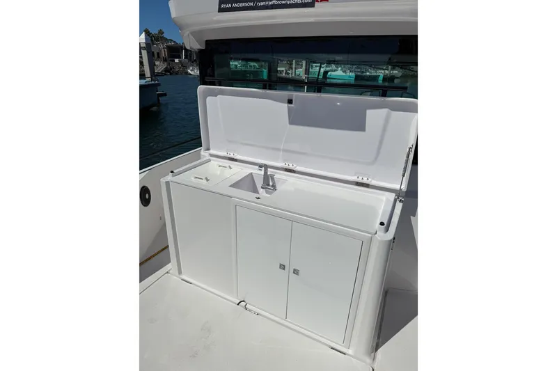 Slide: The Image of 2021 Axopar 28 Cabin BRABUS Trim Wet Bar with sink, open lid, and storage cabinets. - 5
