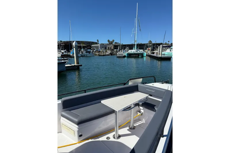 Slide: The Image of 2021 Axopar 28 Cabin BRABUS Trim Wet Bar at marina, featuring sleek seating and table. - 6