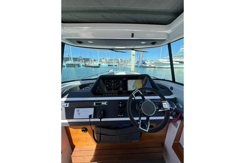 Slide: The Image of 2021 Axopar 28 Cabin BRABUS helm with modern controls, docked at marina. - 8