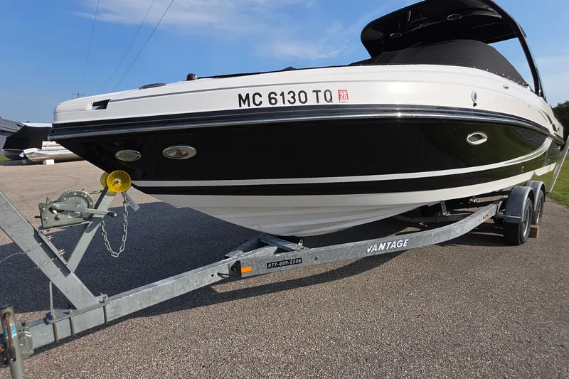 Slide: The Image of 2013 Rinker 276 Captiva Bowrider on trailer, black and white design, parked outdoors. - 1