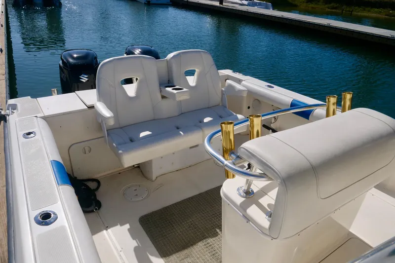Slide: The Image of 1999 Pursuit 2870 Walkaround boat interior with seating and rod holders at a marina. - 10