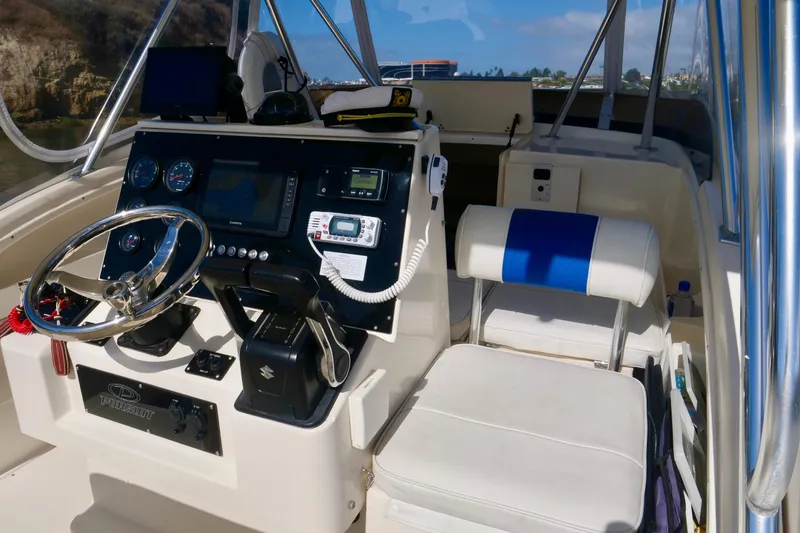 Slide: The Image of 1999 Pursuit 2870 Walkaround boat cockpit with steering wheel and control panel. - 13
