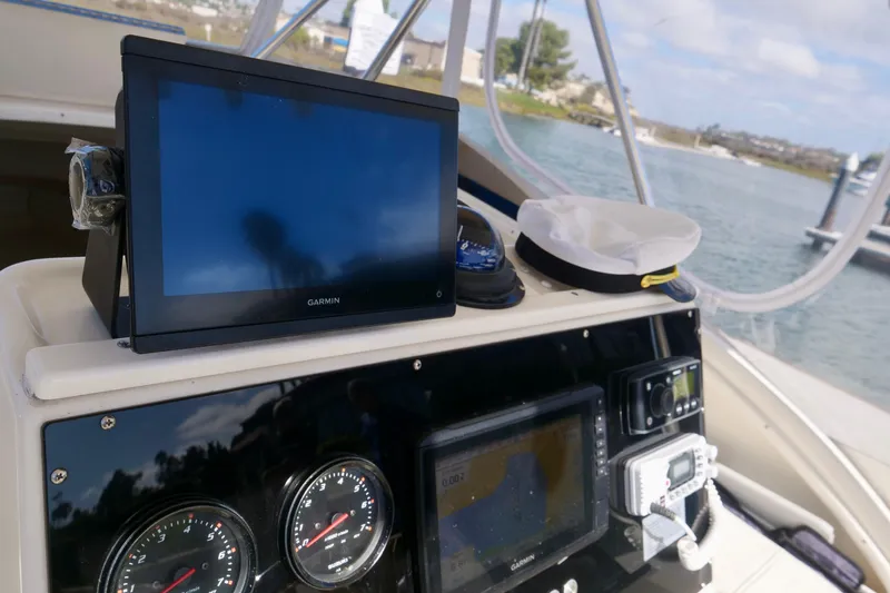 Slide: The Image of 1999 Pursuit 2870 Walkaround boat dashboard with Garmin navigation and captain's hat. - 16