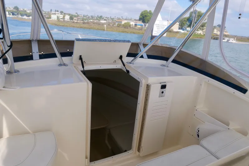 Slide: The Image of 1999 Pursuit 2870 Walkaround boat interior with open cabin door, docked by the water. - 18