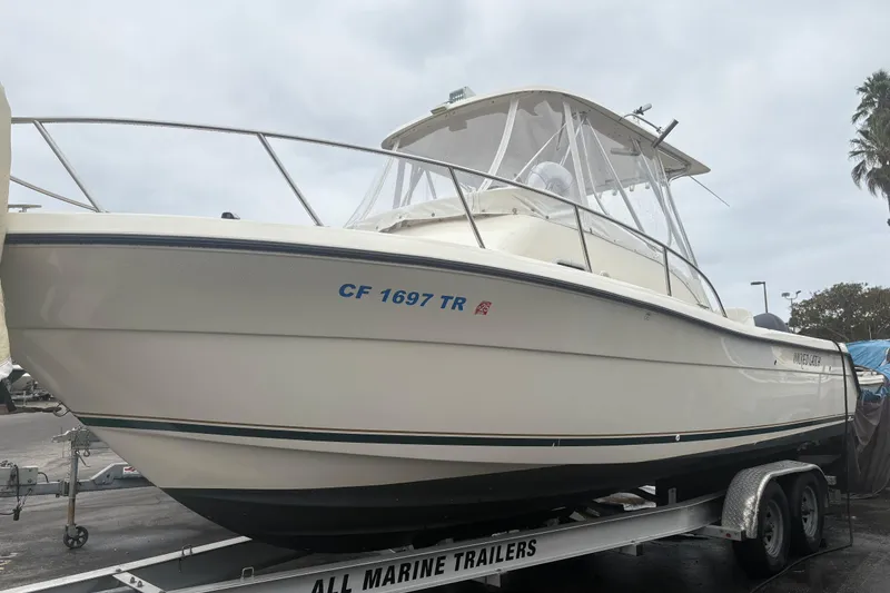 Slide: The Image of 1999 Pursuit 2870 Walkaround boat on trailer, side view, overcast sky. - 21