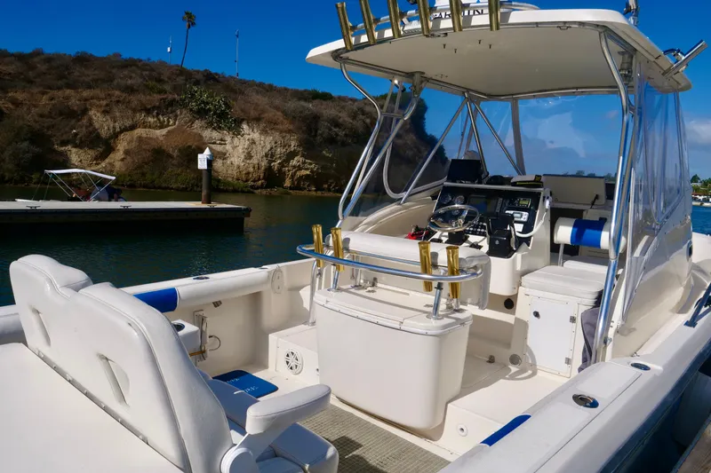 Slide: The Image of 1999 Pursuit 2870 Walkaround boat interior with helm, seating, and fishing rod holders. - 7