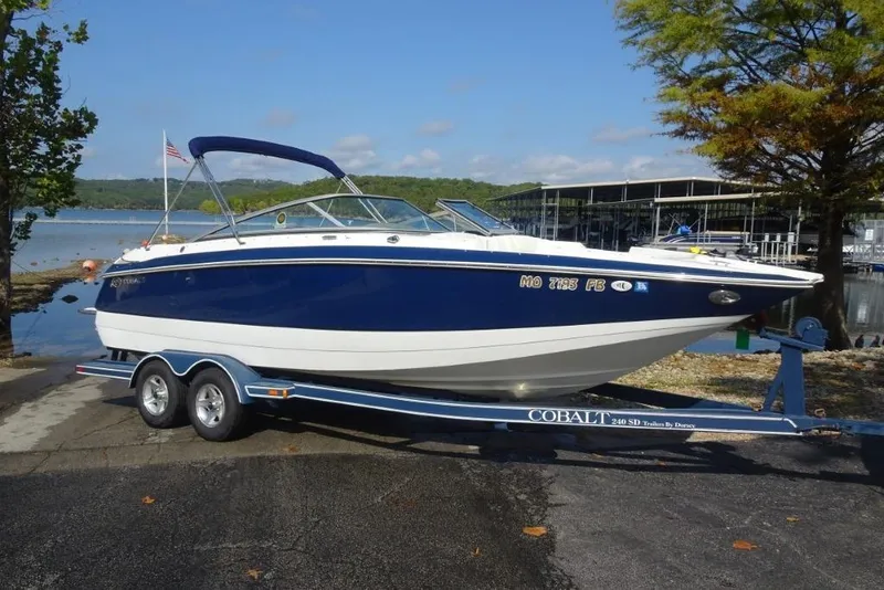Slide: The Image of 2003 Cobalt 24SD boat on trailer by a lake, clear sky background. - 0