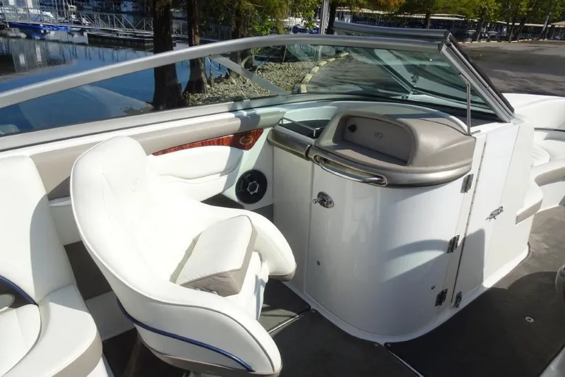Slide: The Image of 2003 Cobalt 24SD boat interior with white seating and dashboard, dockside view. - 15