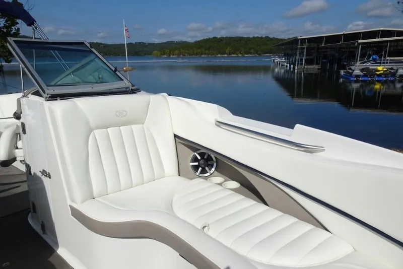 Slide: The Image of 2003 Cobalt 24SD boat with white seating, docked by a serene lake. - 19