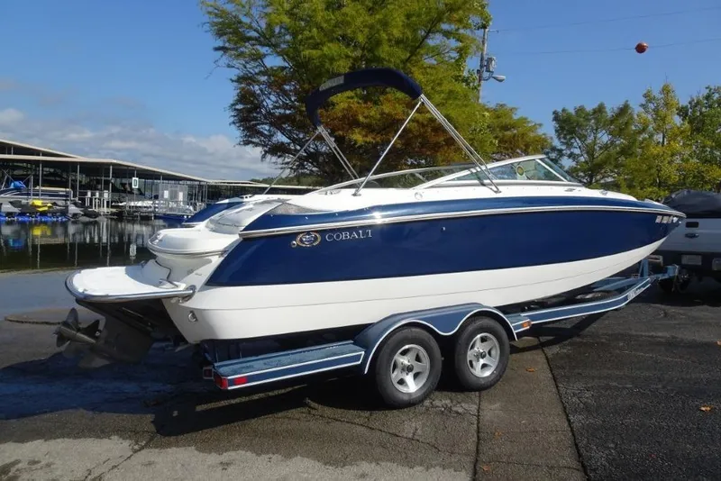 Slide: The Image of 2003 Cobalt 24SD boat on trailer by marina, blue and white design. - 3
