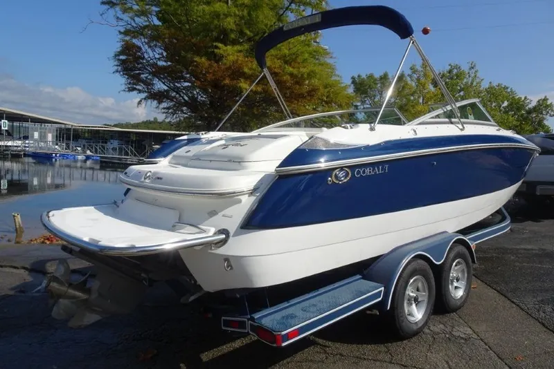 Slide: The Image of 2003 Cobalt 24SD boat on trailer, dockside, with blue and white exterior. - 4
