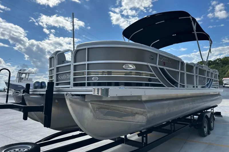 Slide: The Image of 2011 South Bay 925 CR pontoon boat on trailer under a blue sky. - 13
