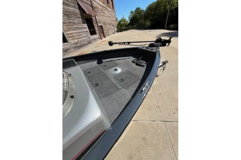 Slide: The Image of 2019 Tracker Pro Guide V-16 SC boat on pavement near rustic building. - 5