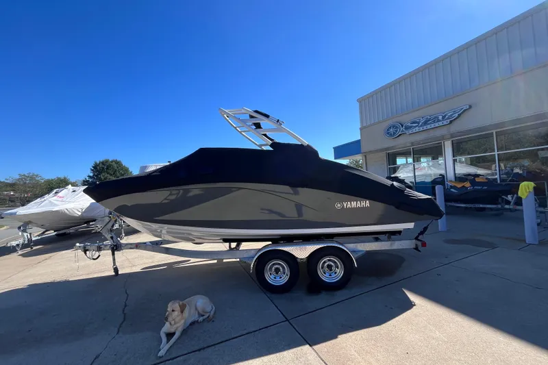 Slide: The Image of 2026 Yamaha Boat 222SE on trailer outside dealership, with a dog resting nearby. - 10