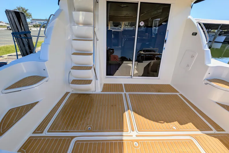 Slide: The Image of 2006 Meridian 411 Sedan yacht deck with wooden flooring and stairs, featuring sliding glass doors. - 6