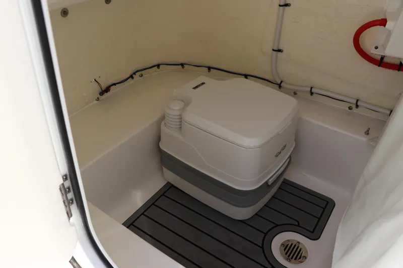 Slide: The Image of 2024 Tidewater 220 LXF boat interior with portable toilet and drainage system. - 36