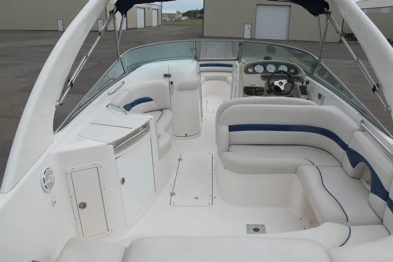 Slide: The Image of 2003 Chaparral 280 SSi boat interior with white seating and dashboard, docked in a marina. - 4