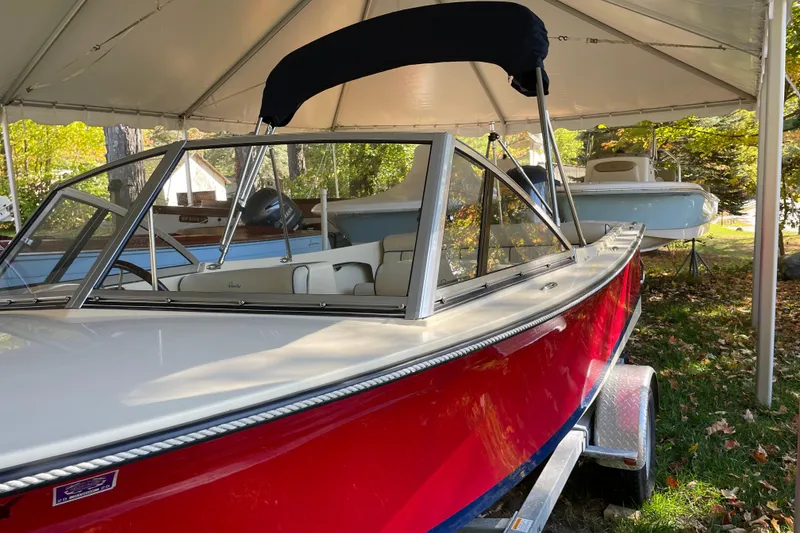 Slide: The Image of 2020 Rossiter 20 Coastal Cruiser boat with red hull under a canopy. - 21