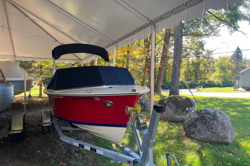 Slide: The Image of 2020 Rossiter 20 Coastal Cruiser boat under canopy, parked on trailer in wooded area. - 5
