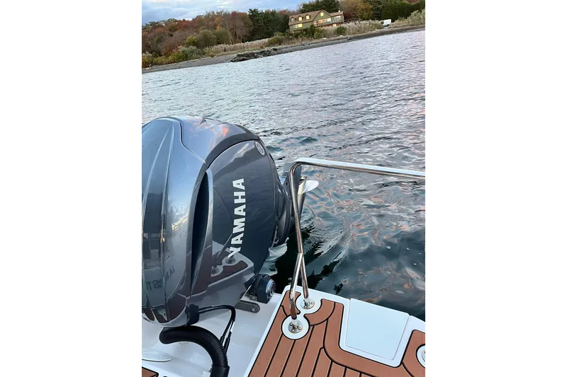 Slide: The Image of 2025 Ranger Tugs R23 with Yamaha outboard engine on calm water near shoreline. - 11