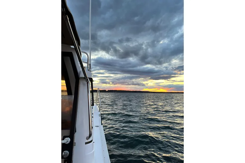 Slide: The Image of 2025 Ranger Tugs R23 boat on water at sunset with dramatic clouds. - 12