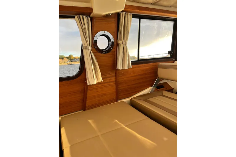 Slide: The Image of Interior of 2025 Ranger Tugs R23 boat with wood paneling and beige seating. - 21