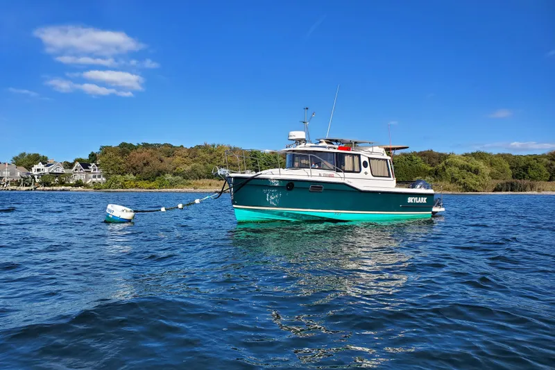Slide: The Image of 2025 Ranger Tugs R23 boat anchored on calm water under a clear blue sky. - 3