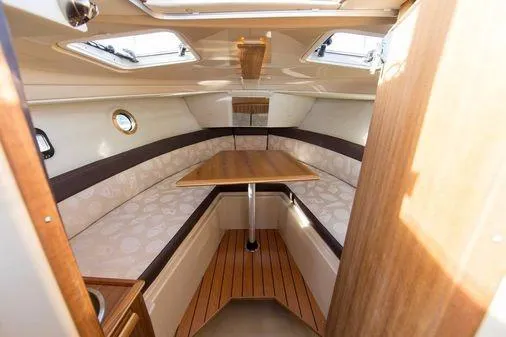 Slide: The Image of 2025 Ranger Tugs R23 cabin interior with seating and table, featuring skylights and wood accents. - 30