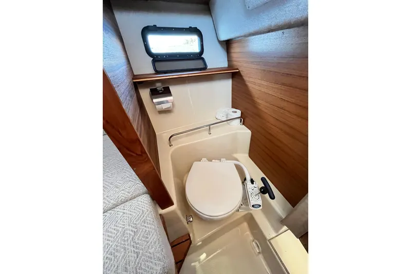 Slide: The Image of 2025 Ranger Tugs R23 boat bathroom with compact toilet and wooden accents. - 34