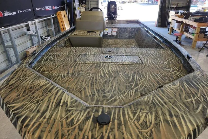 Slide: The Image of 2026 Tracker Grizzly 1648 SC boat with camouflage design in a workshop setting. - 3