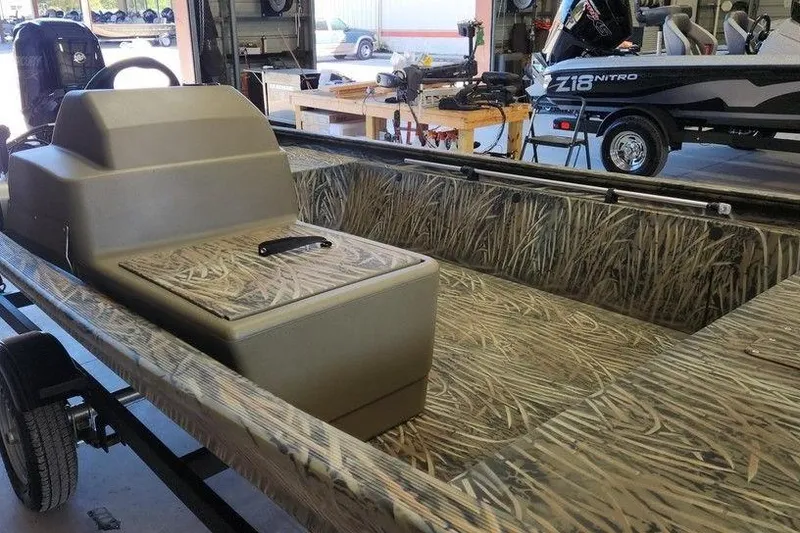 Slide: The Image of 2026 Tracker Grizzly 1648 SC boat with camouflage interior in a workshop setting. - 9