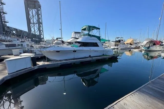 Slide: The Image of 1981 Silverton Convertible yacht docked in a marina, reflecting on calm water. - 2