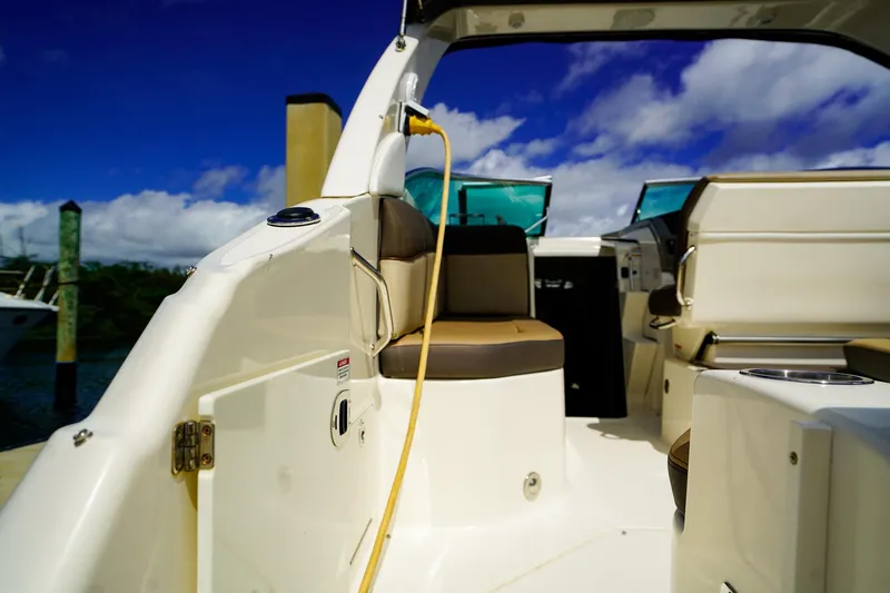 Slide: The Image of 2015 Sea Ray 260 Sundancer boat interior with seating, docked under a blue sky. - 6