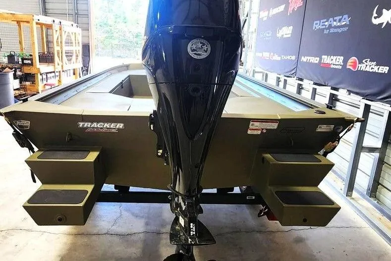 Slide: The Image of 2026 Tracker Grizzly 1654 T Sportsman boat in a showroom, rear view with motor. - 4