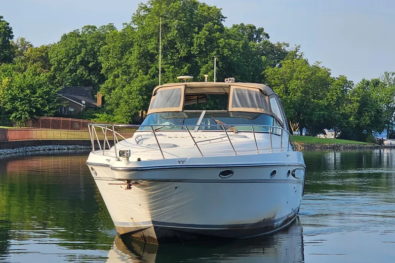 The Image of 1998 Maxum 3700 SCR yacht on calm water, surrounded by lush greenery. - 0