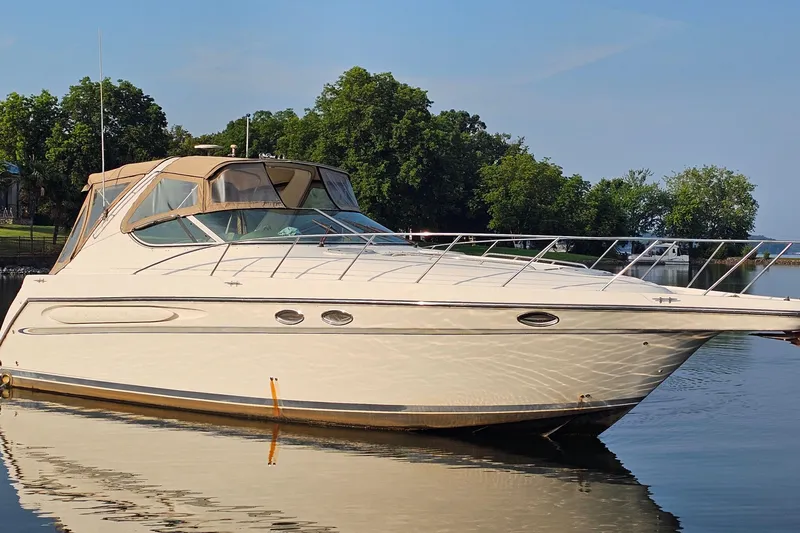 Slide: The Image of 1998 Maxum 3700 SCR yacht on calm water, surrounded by lush greenery. - 1