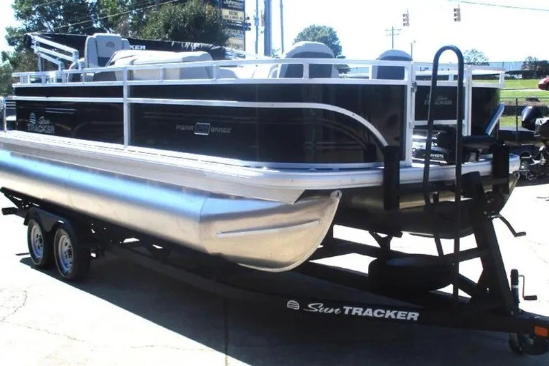 Slide: The Image of 2026 Sun Tracker Fishin' Barge 20 DLX pontoon boat on trailer, parked outdoors. - 4