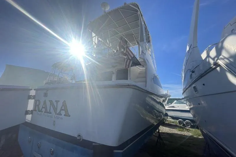 Slide: The Image of 1999 Luhrs Tournament 360 boat with sun flare, docked alongside other vessels. - 9