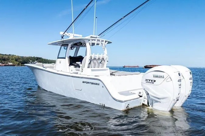 The Image of 2024 Sportsman Open 322 Center Console boat on calm water, clear sky background. - 0