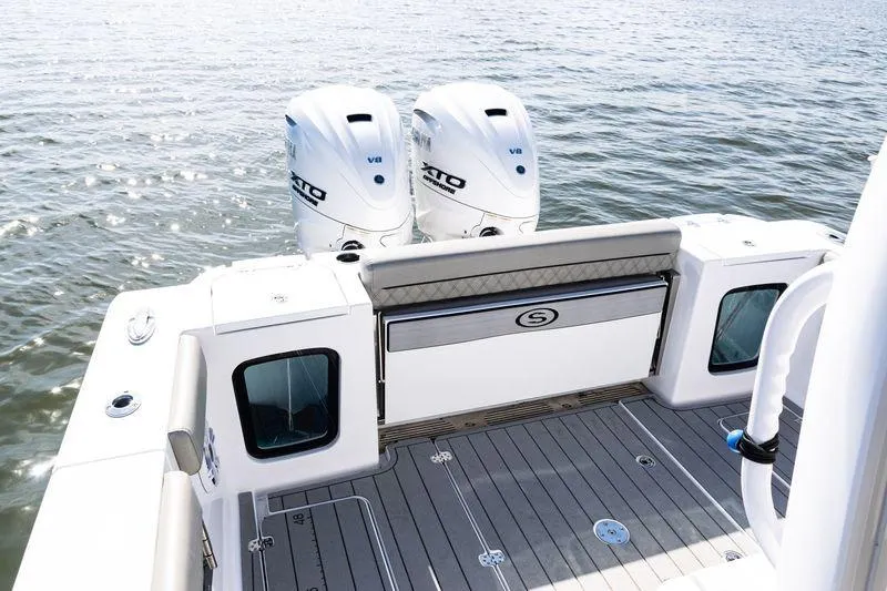 Slide: The Image of 2024 Sportsman Open 322 Center Console boat with rod holders and speakers, under clear blue sky. - 25