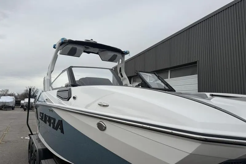 Slide: The Image of 2025 Supra SE 575 boat, sleek design, parked near industrial building. - 5