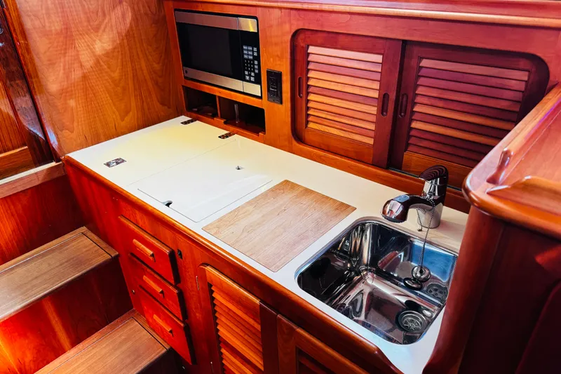 Slide: The Image of Hinckley Picnic Boat MKIII 2012 interior kitchen with wooden cabinetry and stainless steel sink. - 9