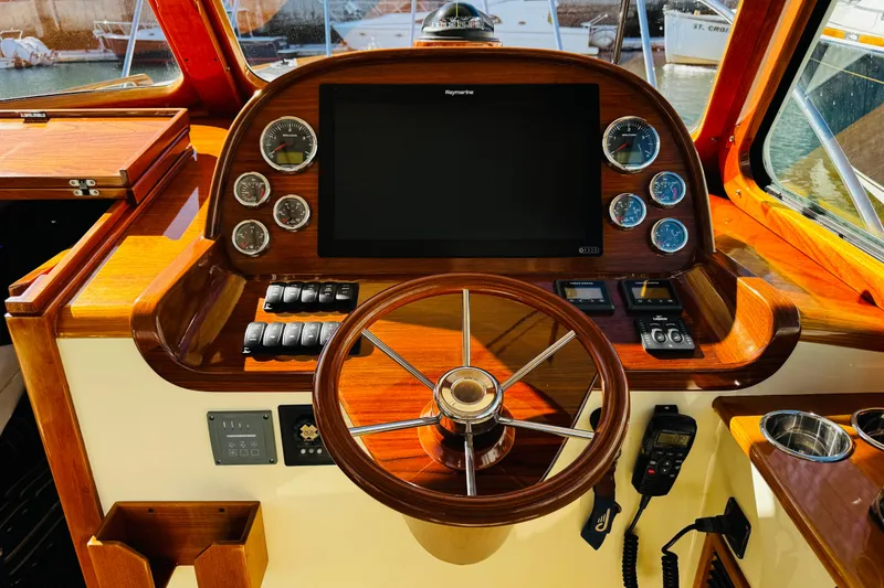 Slide: The Image of 2012 Hinckley Picnic Boat MKIII helm with wooden steering wheel and modern navigation instruments. - 21
