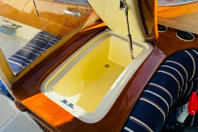 Slide: The Image of Hinckley Picnic Boat MKIII 2012 interior with open storage compartment and striped seating. - 38