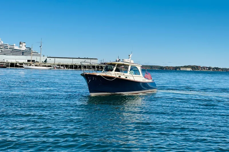 Slide: The Image of 2012 Hinckley Picnic Boat MKIII cruising in a harbor with a large ship in the background. - 57