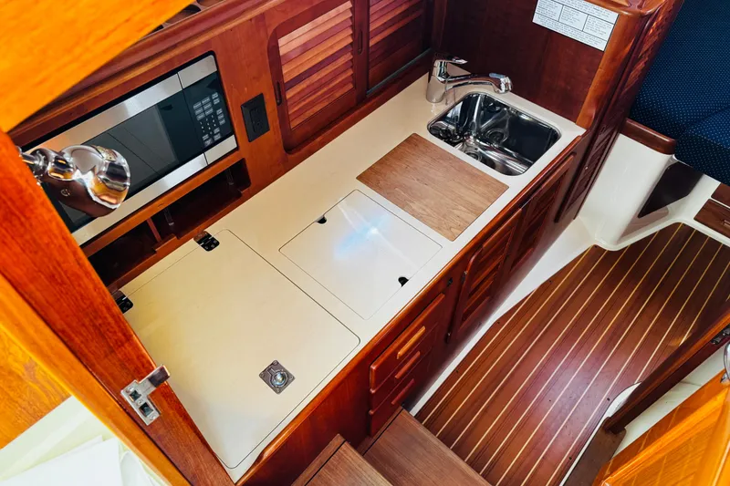 Slide: The Image of Hinckley Picnic Boat MKIII 2012 interior galley with wood cabinetry, sink, and microwave. - 8