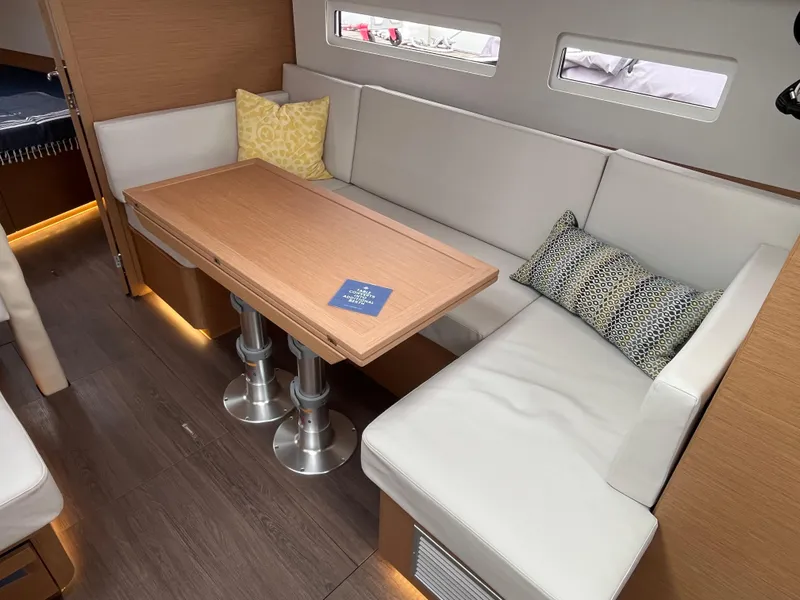 Slide: The Image of 2024 Jeanneau Sun Odyssey 410 interior with modern seating and wooden table. - 17