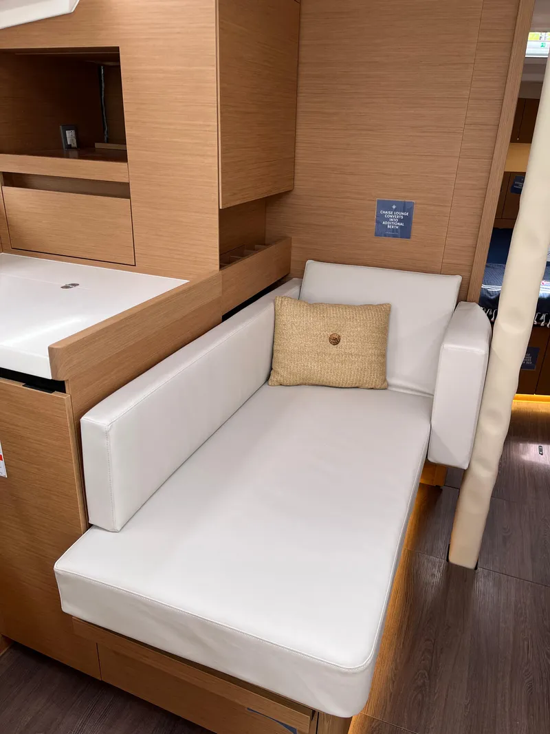 Slide: The Image of 2024 Jeanneau Sun Odyssey 410 interior with white cushioned seating and wooden cabinetry. - 19