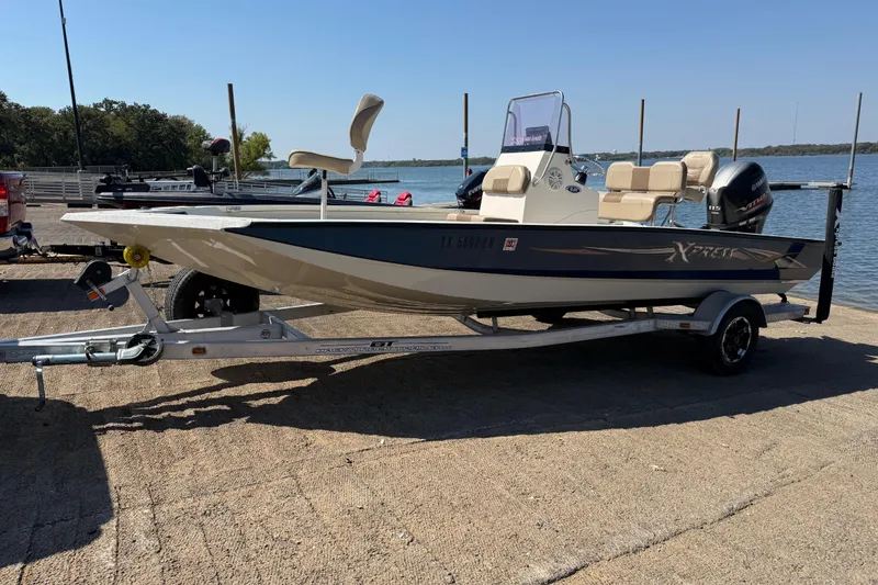 Slide: The Image of 2018 Xpress H20B Bay boat on trailer by a lake. - 30